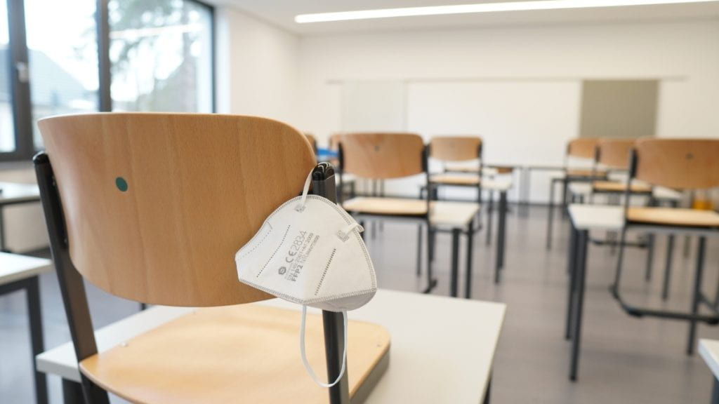 Empty classroom with a face mask hanging on one chair