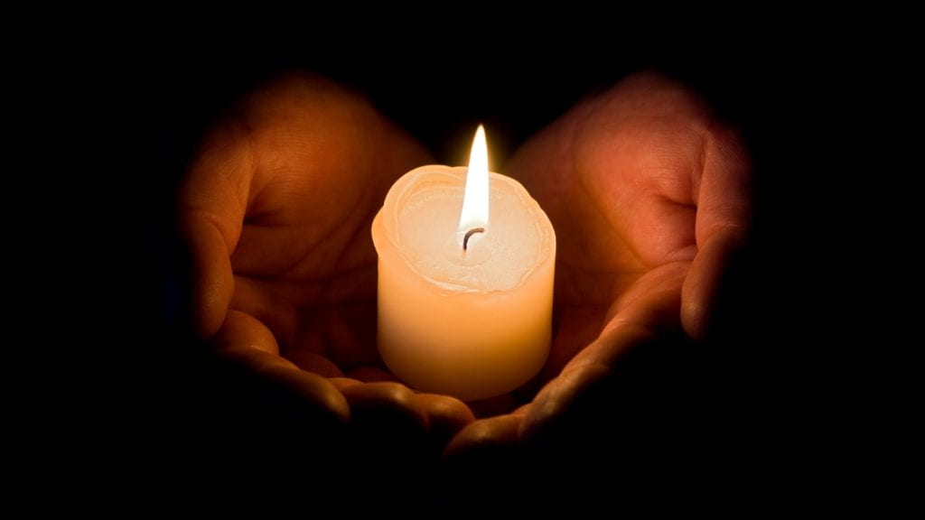 A light candle is held in the palm as a memorial