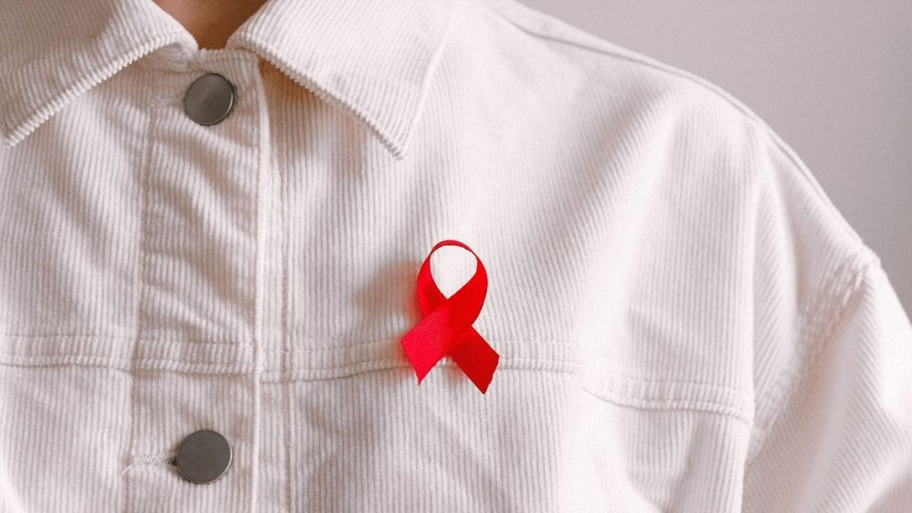 A red ribbon attached to a person's shirt for HIV awareness