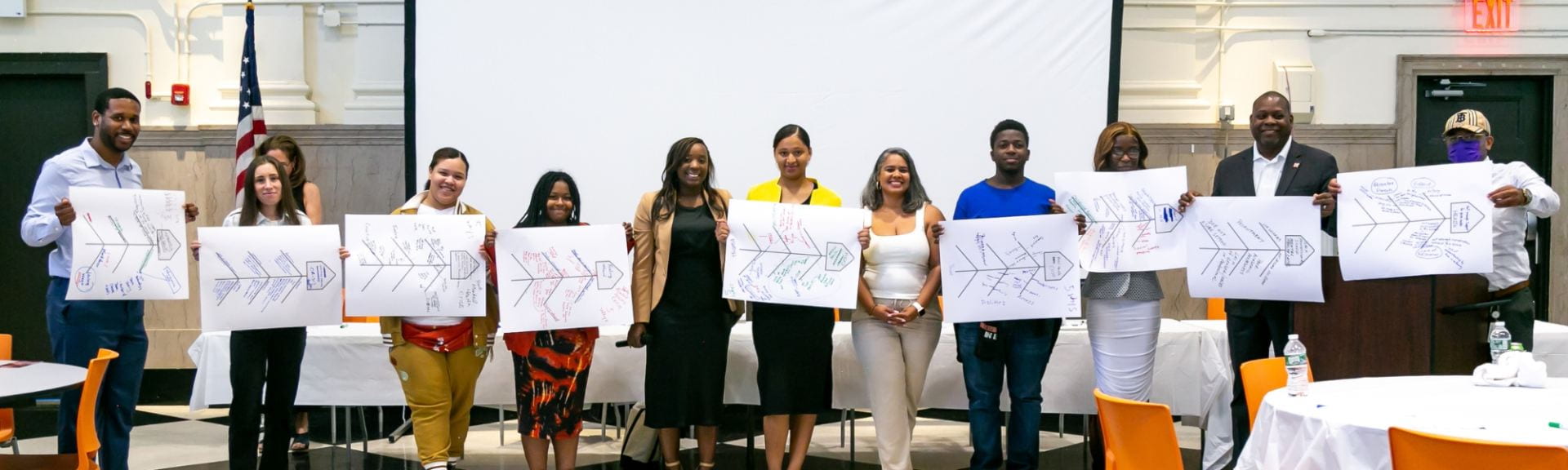 Students and IPP alum holding fishbone diagrams standing in front of a conference room