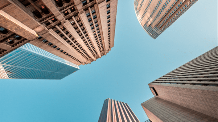 A perspective shot of buildings in a city from the ground looking up toward the sky