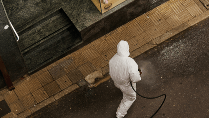 A person cleaning the street wearing a hazmat suit