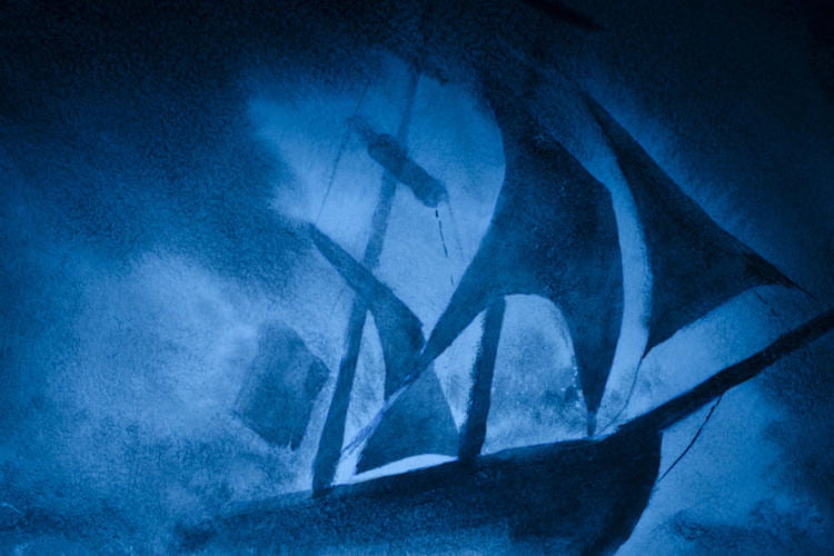 A dark blue sailboat during a storm