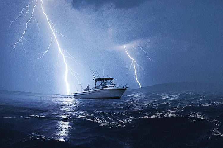 A boat in the middle of the ocean at night with two lightning bolts on either side of it