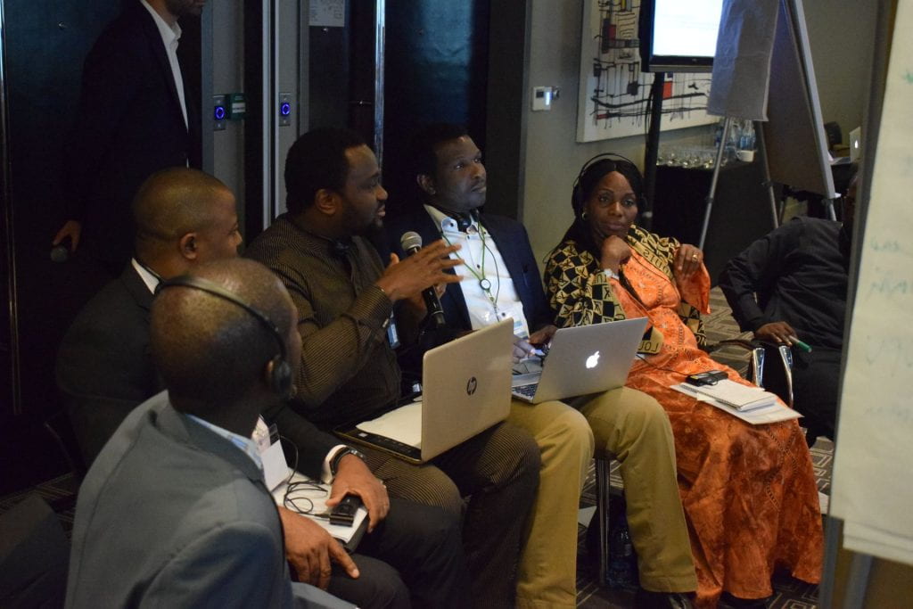 Nigeria team seated with laptops in lap, using the microphone to speak