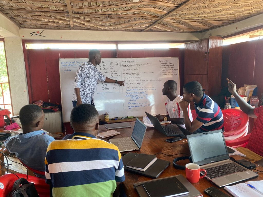 Sierra Leone team working together on the PDIA process and pointing at notes a the whiteboard