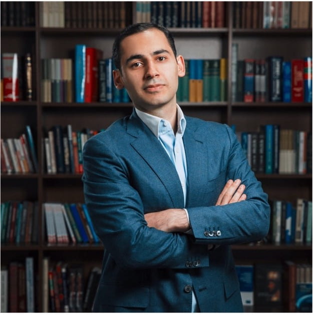 Urkhan Seyidov headshot standing in front of a bookshelf
