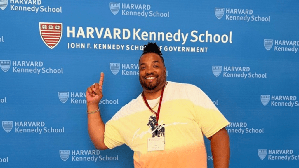 Joe N. Savage Jr. pointing to Harvard Kennedy School signage