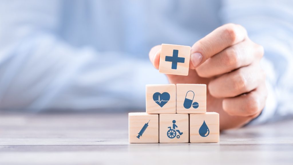Hand arranging wooden blocks with healthcare icons