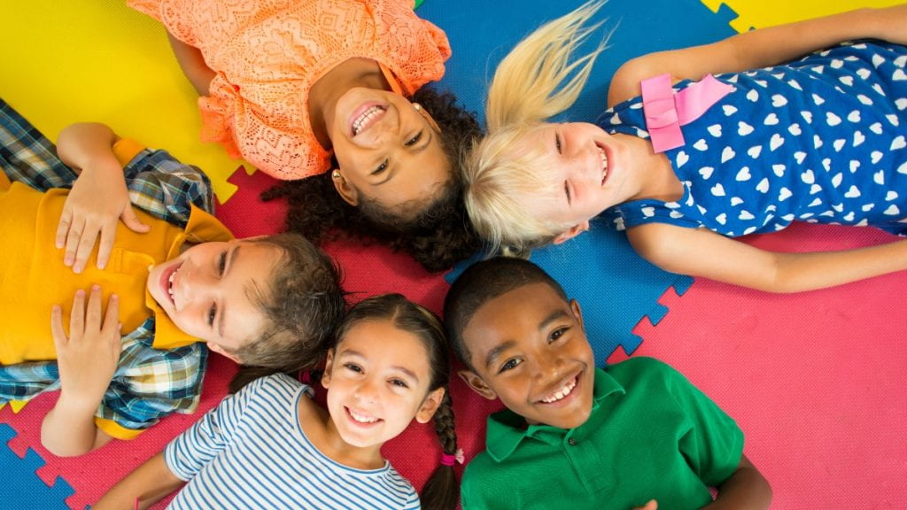 Diverse group of children laying down looking up at the camera