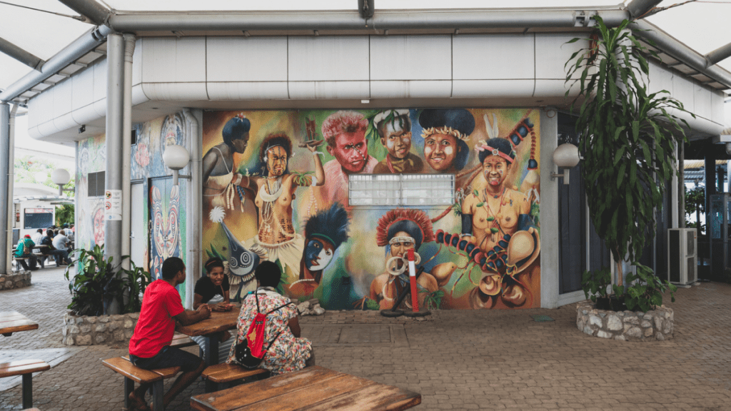 People sit out side the terminal near a beautiful mural at Jacksons International Airport in Port Moresby, Papua New Guinea