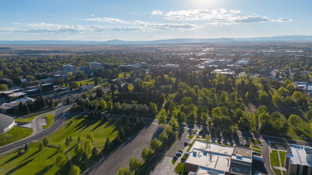 A drone shot of Laramie Wyoming neighborhood's cityscape with greenery, sunlight and cloudy sky
