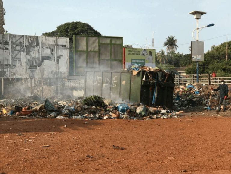 an image of trash burning in an open trash can outside a building
