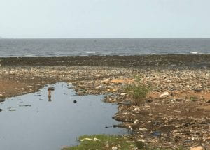 garbage in the grass and in water in an open field