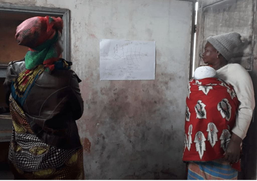 women look at a piece of paper on the wall
