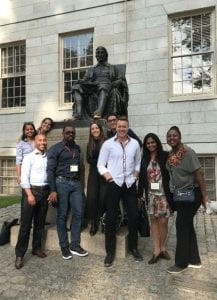 a group standing in front of the John Harvard statue
