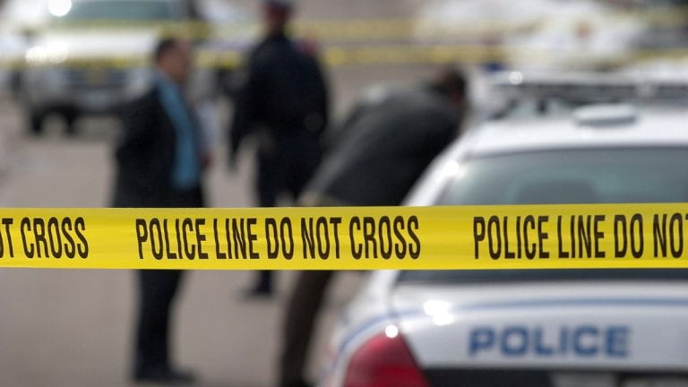 Crime scene tape in front of police cars