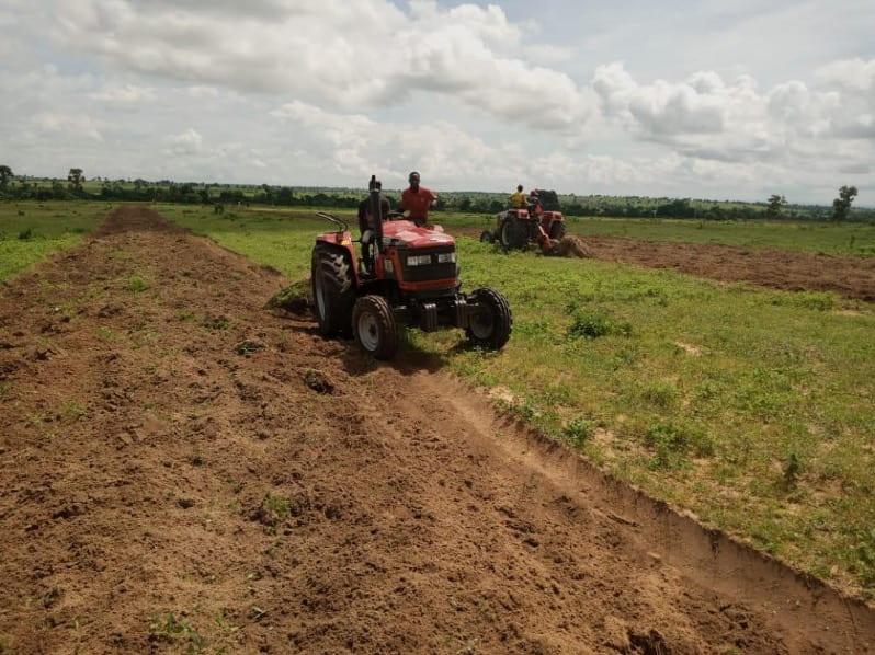 2 people driving a tractor and cultivating the land