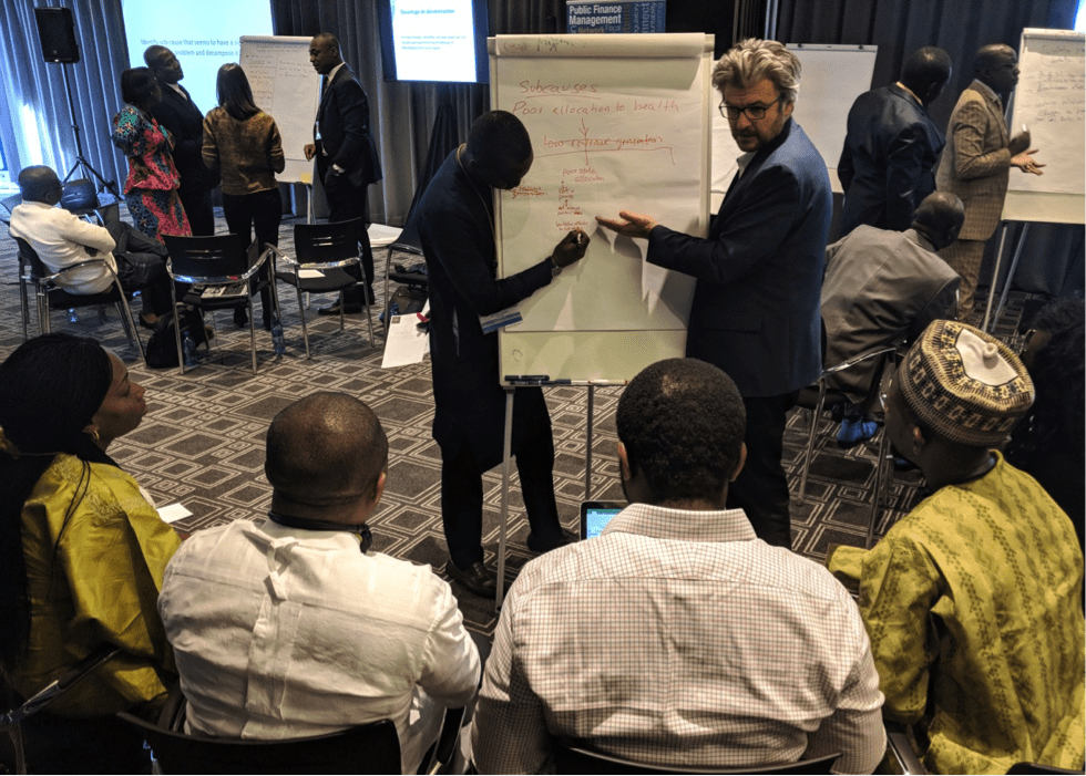 Matt Andrews speaking with participants and pointing to white board