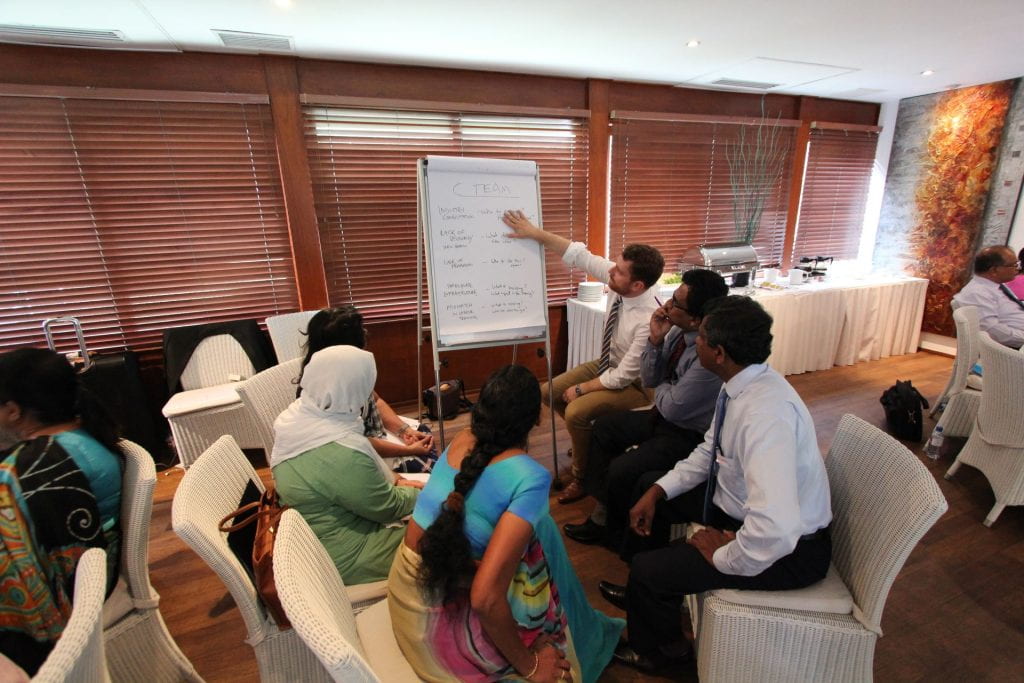 People in Sri Lanka gathered in a semi circle around a man pointing to a whiteboard