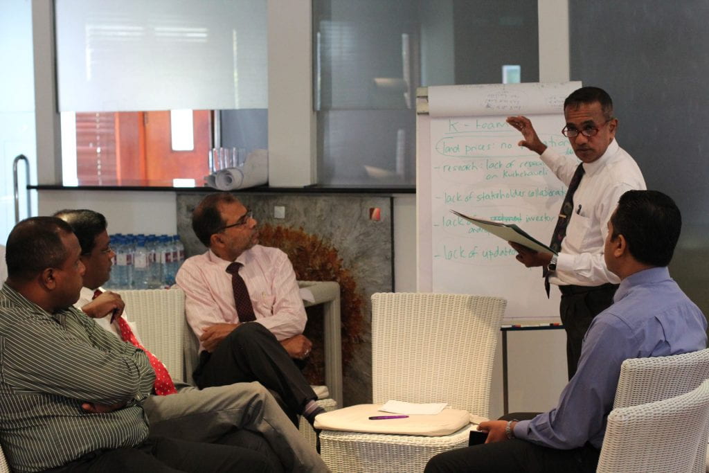 Sri Lanka participant talking and standing in front of a whiteboard with group members listening