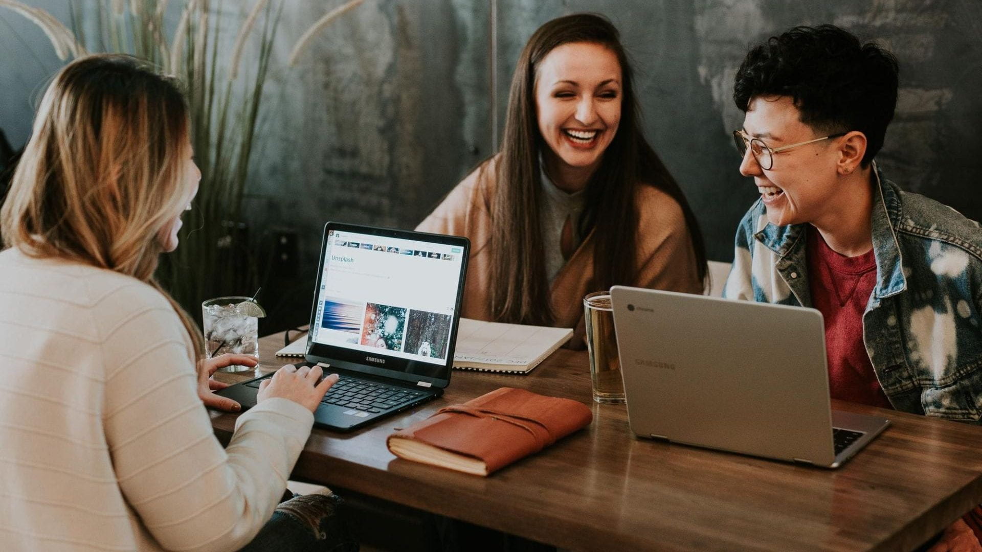 People working on computers at a table and laughing