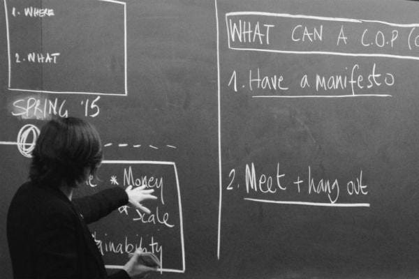 Salimah Samji pointing at a chalkboard with notes about building a community of practice