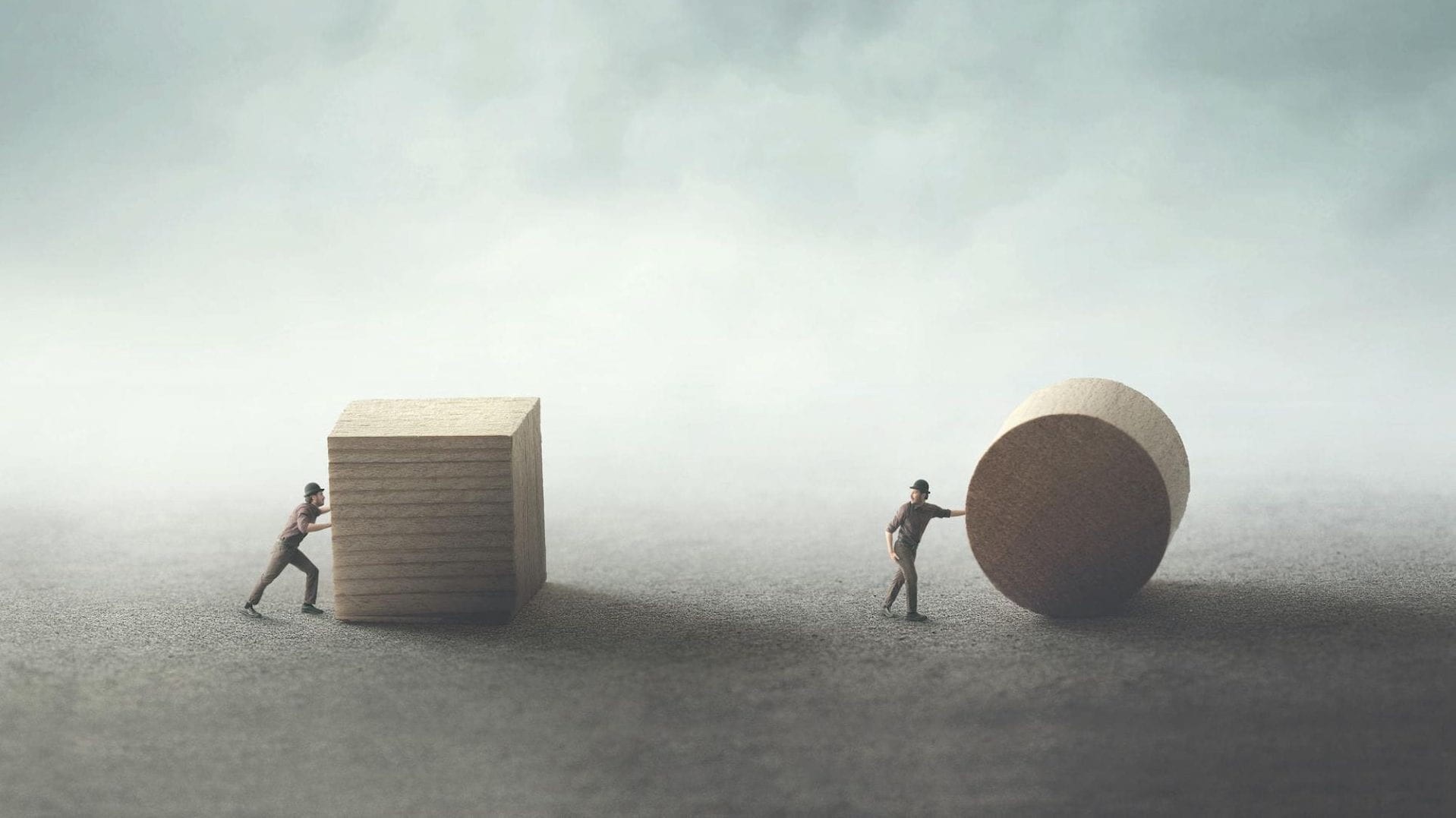 A person pushing a lifesize block next to another person pushing a lifesize cylinder