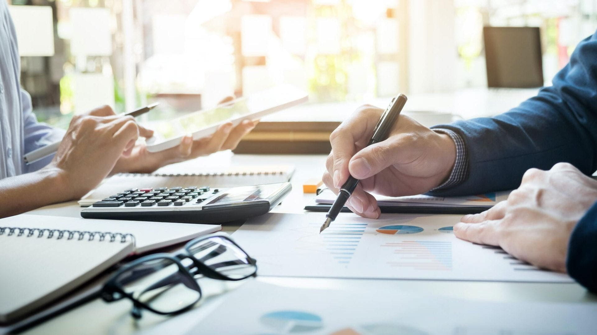 2 people at a table writing notes and looking at graphs and figures