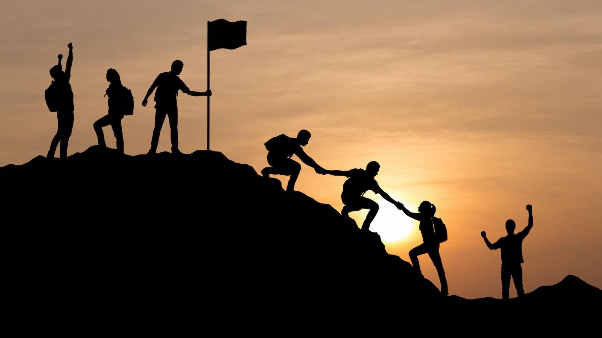 Silhouette of people climbing a mountain