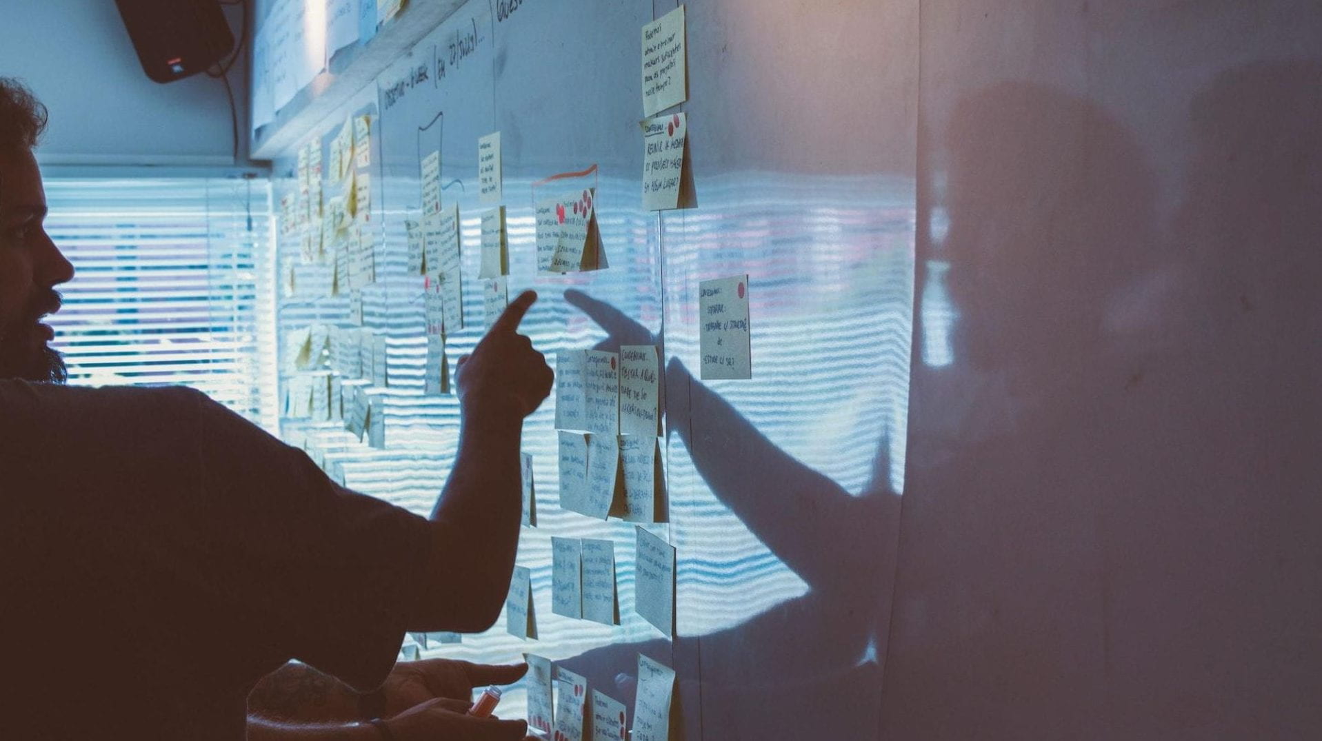 A person pointing to a wall with post-it notes