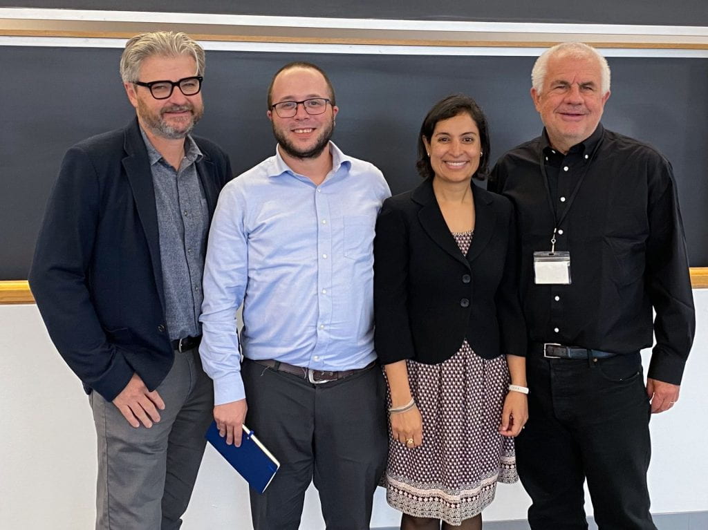 Matt Andrews, Dan Honig, Salimah Samji, and Lant Pritchett smiling in front of a blackboard