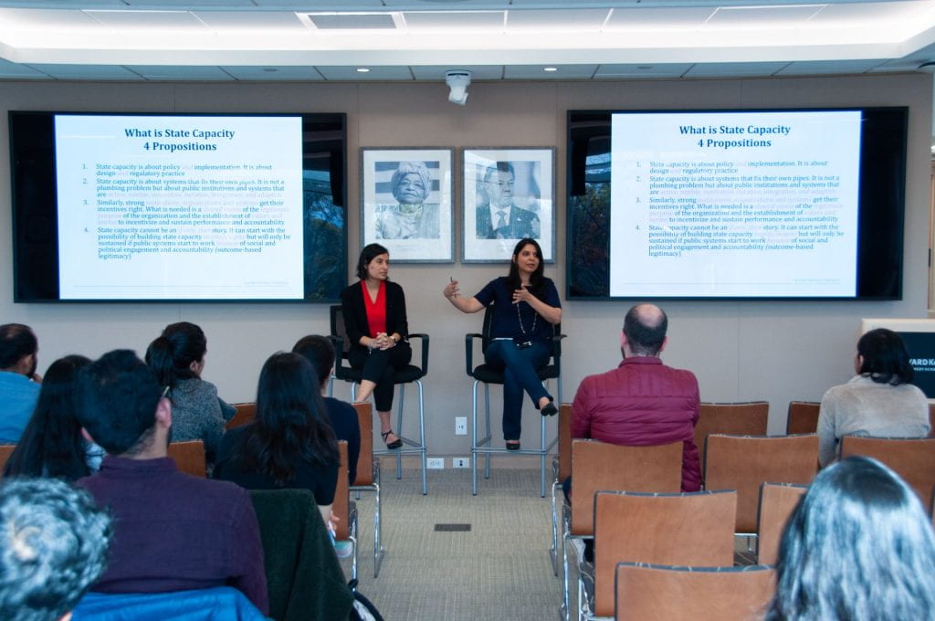 Yamini Aiyar and Salimah Samji seated and presenting in front of students with slide projections behind them
