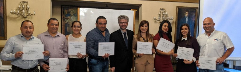 Matt Andrews standing next to participants from Honduras holding certificates of completion