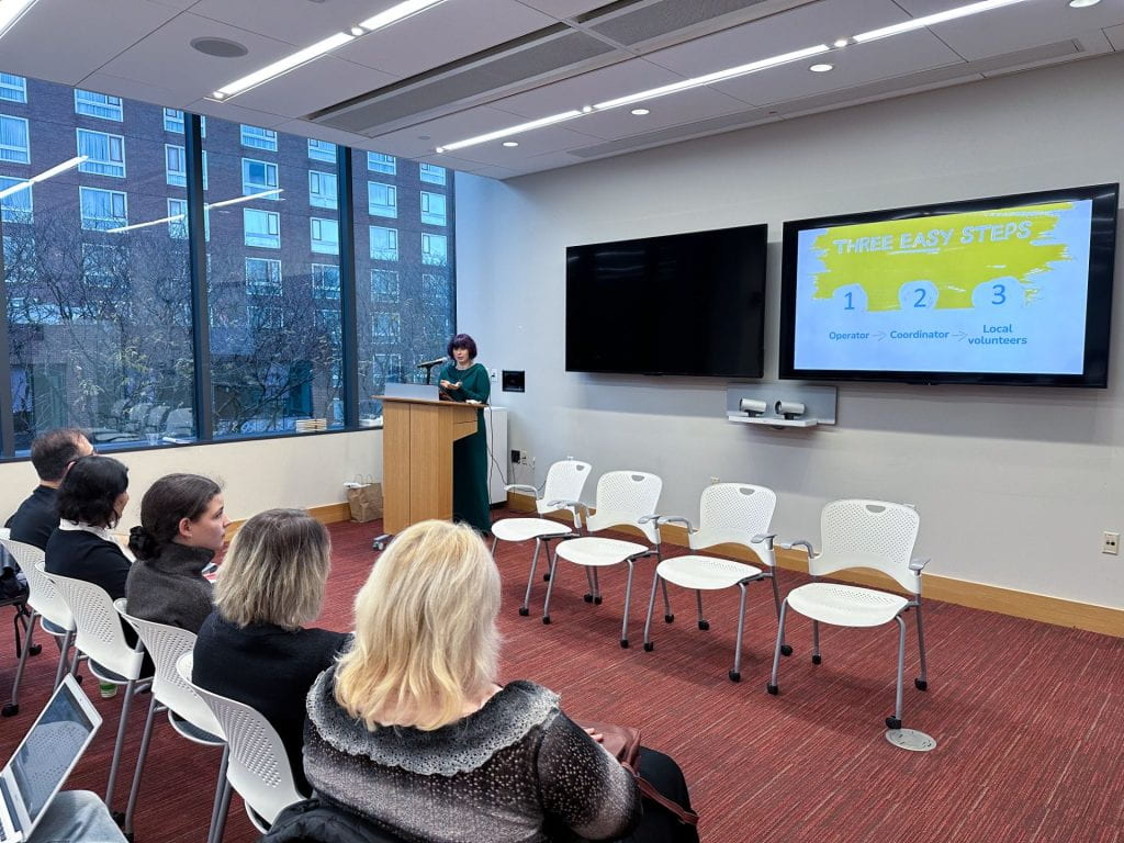 Rita Vinokur presenting with fellow panelists seated in the front row.