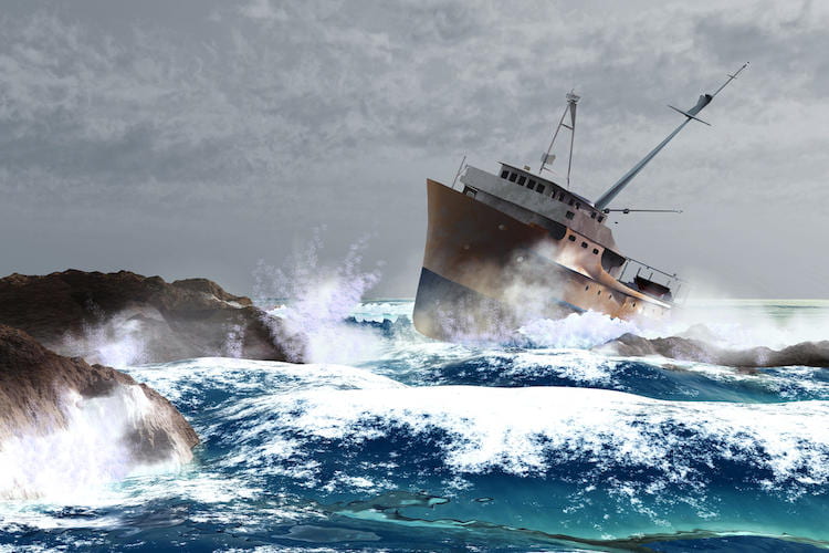 A ship in waves about to hit a rocky shoreline