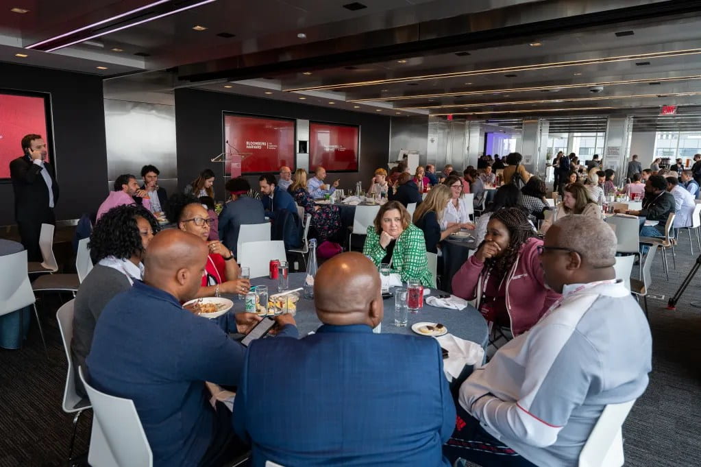 A crowded room of Bloomberg Harvard participants eating lunch
