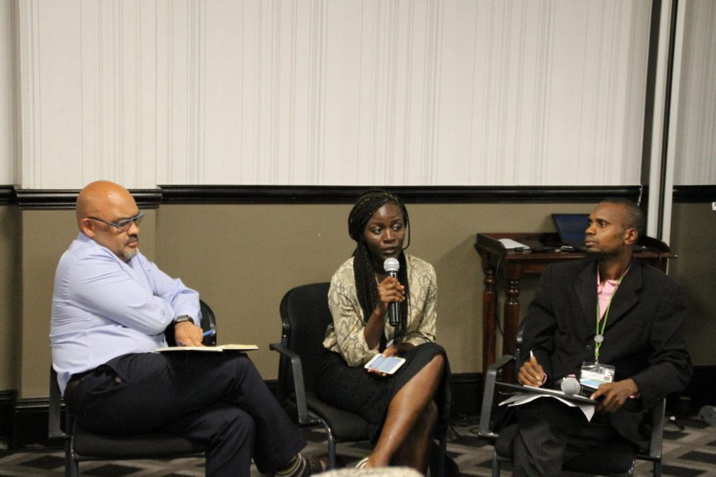 The Gambia team participant presenting with teammates on either side