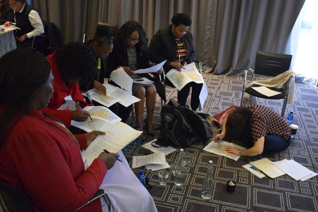 Lesotho team working together and looking at printed maps of the United States