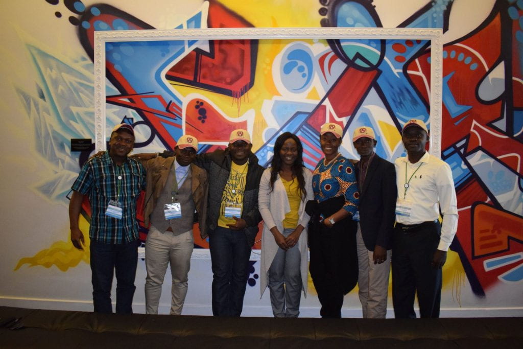 Liberia team group photo in front of a colorful yellow, red, and blue abstract art wall