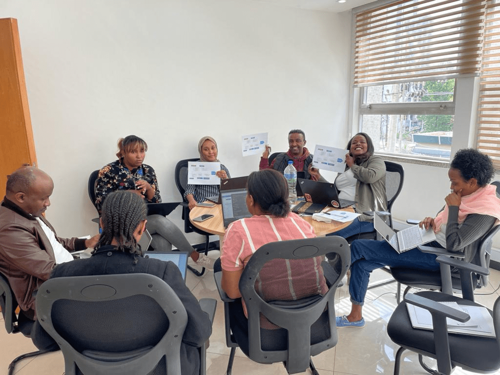 Team sitting around the table holding papers with fishbone diagrams.