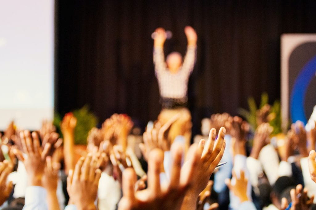 People with hands raised celebrating with person in background with hands raised