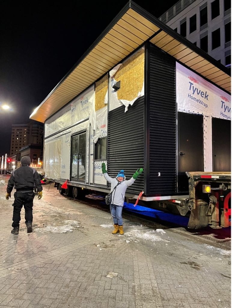 A warming chalet for ice skaters with a person posing with arms raised above head