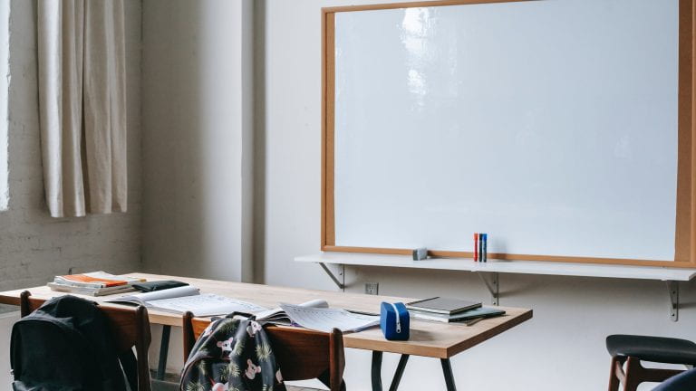 An empty classroom with a blank whiteboard