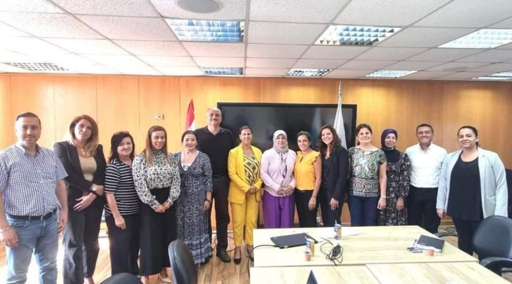 Group of people lined up together posing for a picture taken at the front of a conference room
