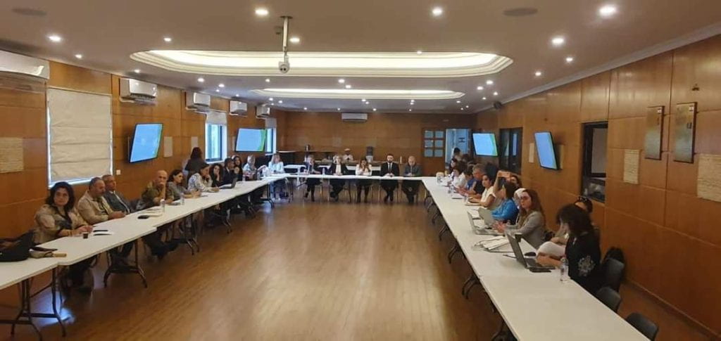 Group of people around a conference room table listening to a presentation