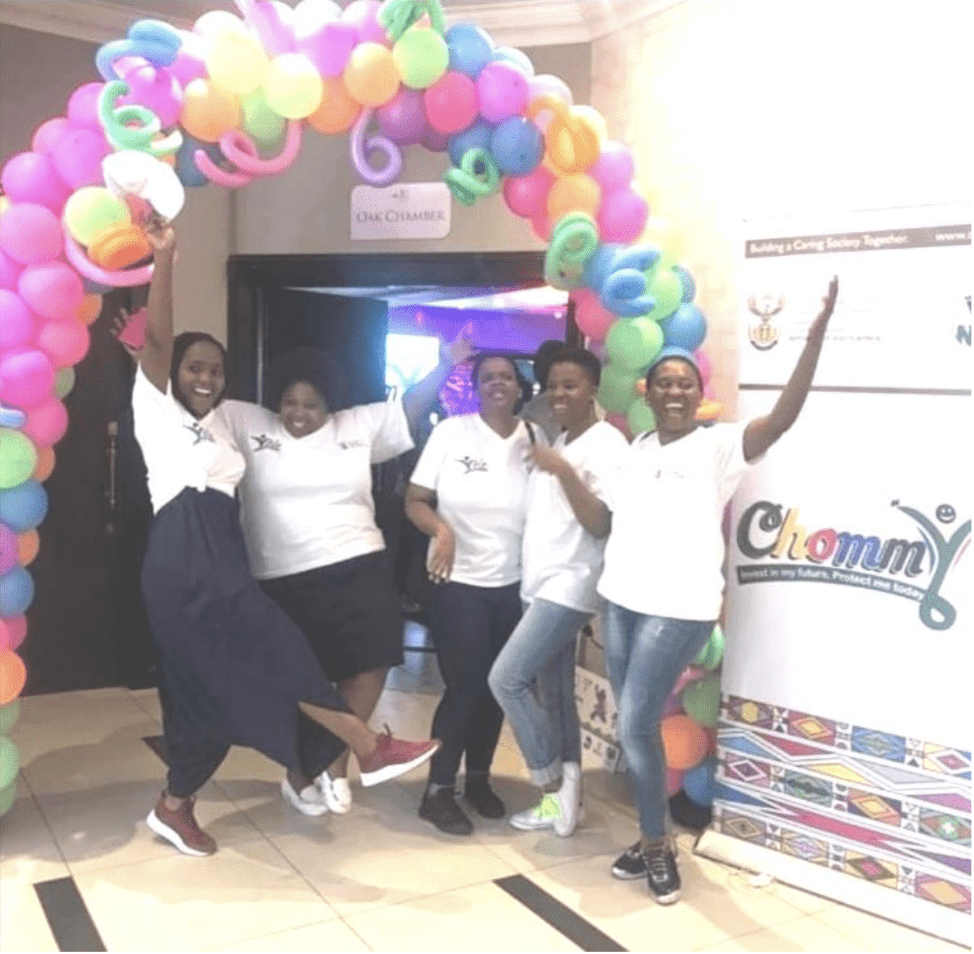 Happy people celebrating under balloon archway
