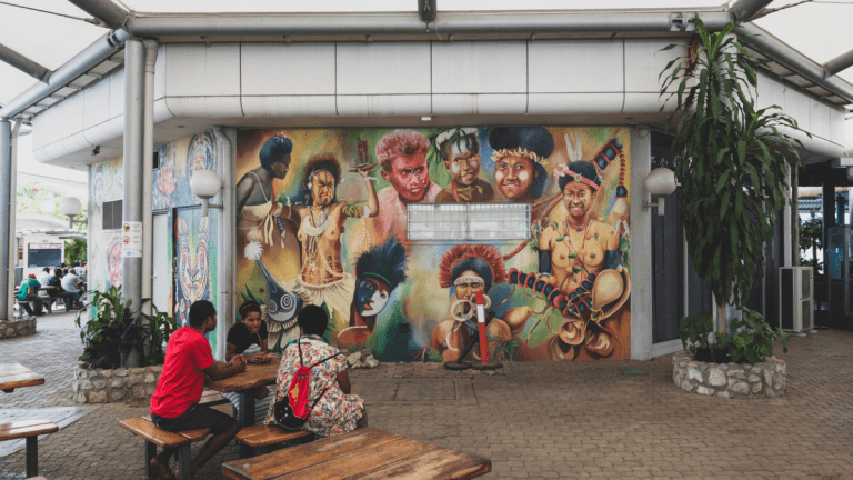 People sit out side the terminal near a beautiful mural at Jacksons International Airport in Port Moresby, Papua New Guinea