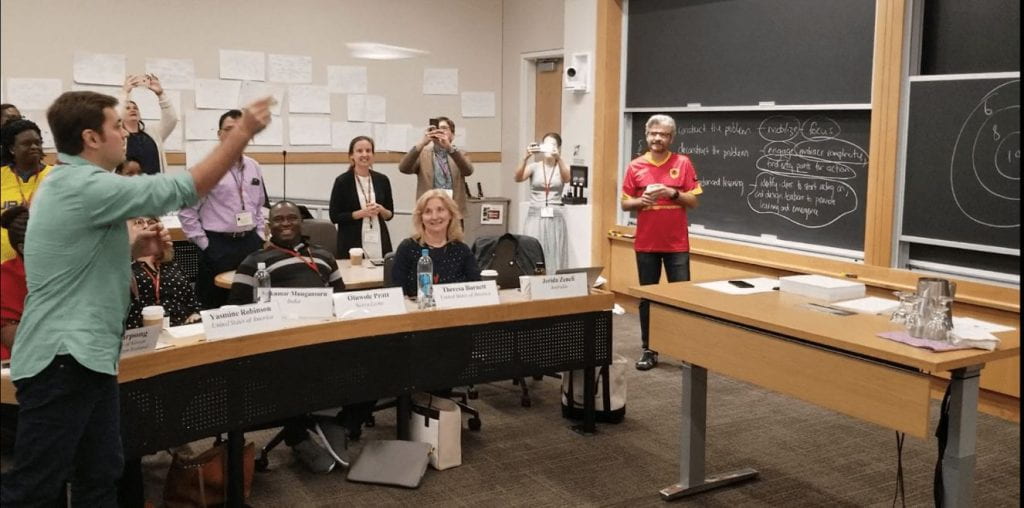 Participant throwing a paper airplane at a bullseye in front of classroom