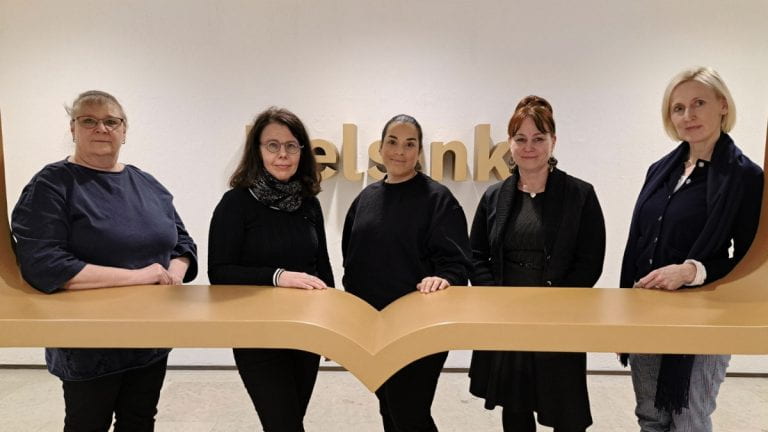 Team participants in front of "Helsinki" written on wall